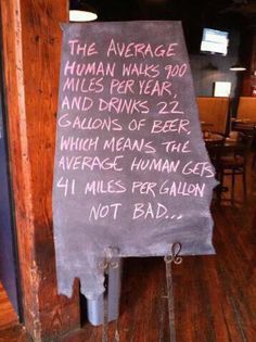 a sign that is on the side of a wall in a restaurant saying, the average human walks 100 miles per year and drinks 2 gallons of beer which means the average human gets