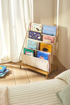 a bookshelf filled with children's books next to a bed