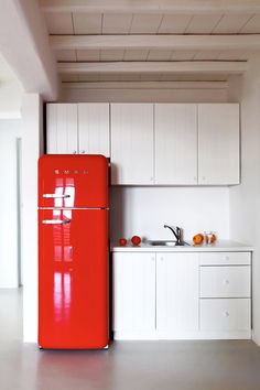 a red refrigerator freezer sitting inside of a kitchen