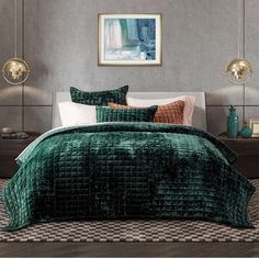 a bed with green velvet comforter and pillows