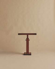 a small wooden table sitting on top of a white floor next to a brown wall