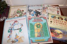 four children's books are sitting on the floor next to a christmas tree and stockings