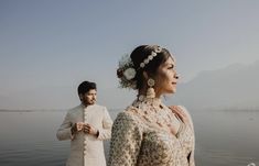 a man standing next to a woman on top of a body of water with flowers in her hair