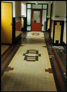 an empty hallway with tiled floors and yellow doors