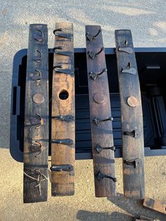 three pieces of wood with metal handles on top of each other in front of a trash can