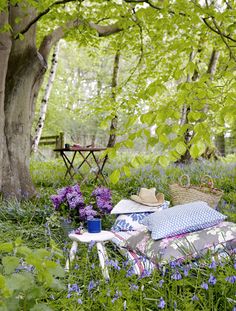 a chair sitting in the middle of a forest filled with purple flowers and other items