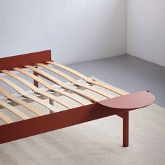 a bed frame with wooden slats on the top and bottom, in an empty room