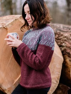 a woman standing next to a tree trunk holding a cup