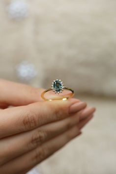 a woman's hand holding an engagement ring with a green stone in the middle