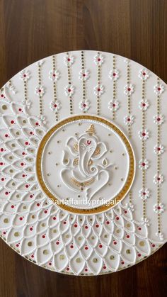 a white plate with gold and red designs on the edge, sitting on a wooden table