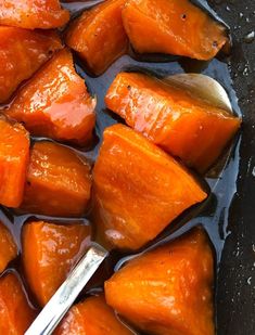 cooked carrots are in a pan with a spoon