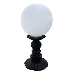 a white ball is on top of a black stand