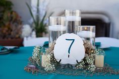 the table is set with candles, flowers and seashells for an ocean themed centerpiece