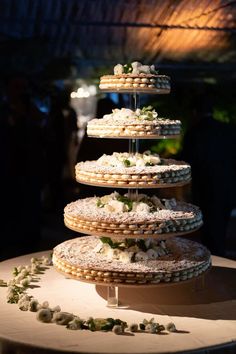 a three tiered cake stand with cookies and flowers on the top, as well as other desserts