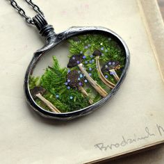 a necklace with green plants and mushrooms in it