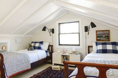 two beds in a room with white walls and wood trim on the ceiling, along with a blue rug