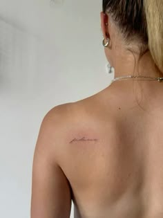 the back of a woman's shoulder with a small tattoo on her left side