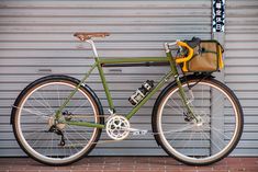 a green bike parked in front of a garage door with a bag on the back