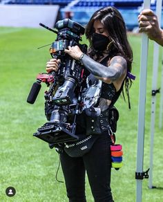 a woman holding a camera on top of a field