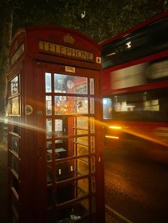 a red phone booth sitting on the side of a road next to a street light