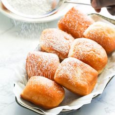 powdered sugar sprinkled on top of pastries in a metal bowl with spoon