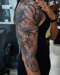 a man with a lion and cross tattoo on his arm is taking a selfie