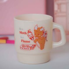 a coffee cup sitting on top of a table next to a pink book case and pencils