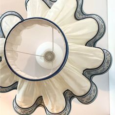 a white and blue flower shaped light fixture hanging from the side of a wall next to a mirror