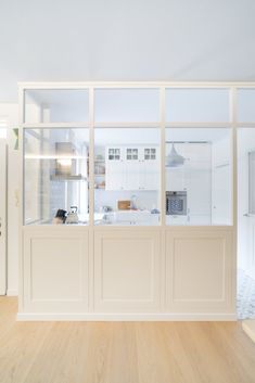 an empty kitchen with wooden floors and white cabinets in the backround is seen from across the room