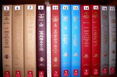 a row of books sitting on top of a wooden book shelf next to each other