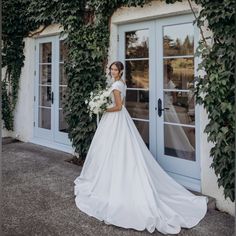 a woman standing in front of a building wearing a wedding dress