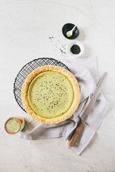 a pie sitting on top of a white table next to a knife and some condiments