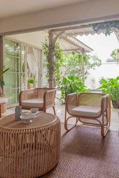 a living room with wicker furniture and potted plants