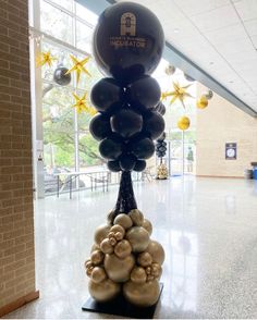 an inflatable balloon tree with gold and black balloons on it at the airport