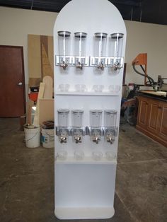 a white display case filled with glasses on top of a floor next to a counter