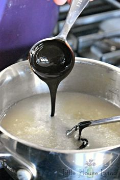 a person pouring liquid into a pot on top of a stove with a ladle