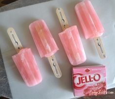 four popsicles sitting on top of a table next to a box of jello