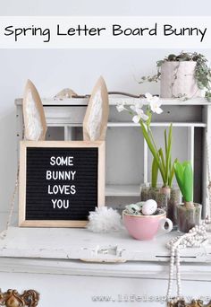 some bunny ears are sitting on top of a white shelf next to flowers and eggs