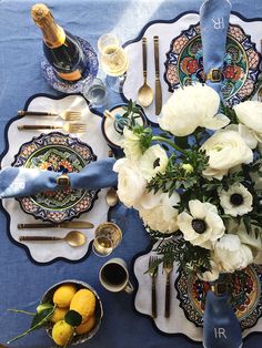 the table is set with blue and white plates, silverware, and flowers in vases