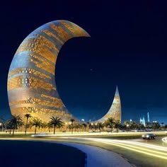 an artisticly designed building in the middle of a city at night with cars passing by