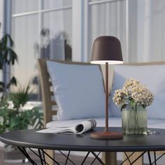 a table with a lamp and flowers on it in front of some couches outside