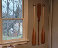 two wooden oars hanging on the wall next to a window