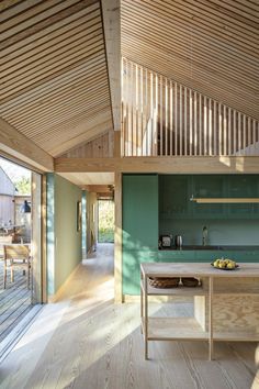 an open kitchen and dining area in a house with wooden floors, green walls and ceiling