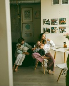 three people are sitting in a room with pictures on the wall and one person is brushing their teeth