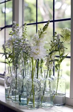 several vases filled with flowers sitting on a window sill