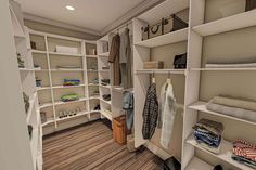 a walk in closet filled with lots of white shelves and clothes on top of wooden flooring