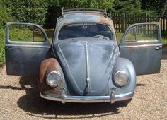 an old car is parked in the gravel