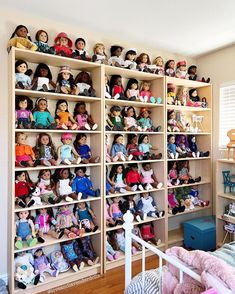 there are many dolls on the shelves in this child's room, all lined up