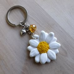 a white flower with yellow center sitting on top of a wooden table next to a keychain