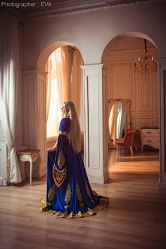 a woman in a blue and gold dress is sitting on the floor with her back to the camera